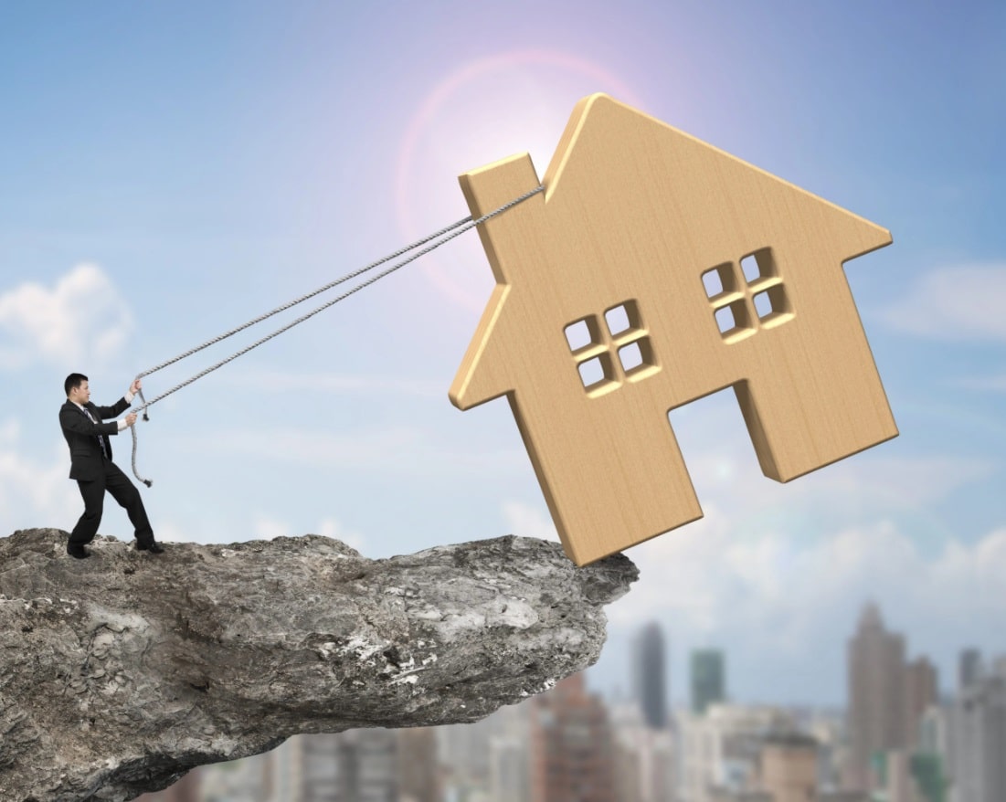 Agent immobilier qui tire par des cordes une maison en bois