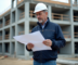 Chef de chantier examine plans sur un site en construction