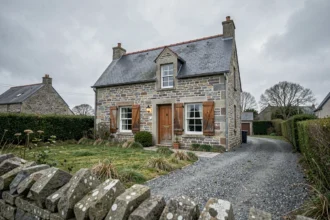 Maison en pierre bretonne à vendre dans le Finistère 29, façade en granite avec volets blancs et jardin négligé, ambiance mélancolique d'une vente urgente cause divorce